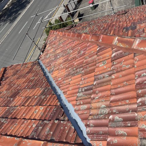 Metal valley between two terracotta tiled roof sections above a street